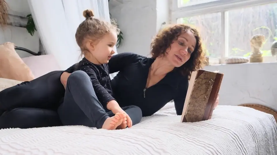 Grabación referencial de una madre y su hija compartiendo un libro en casa.